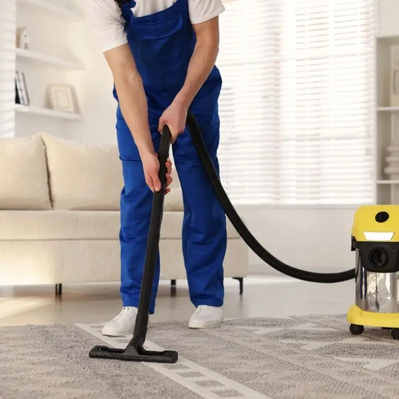 cleaning service worker vaccuming rug