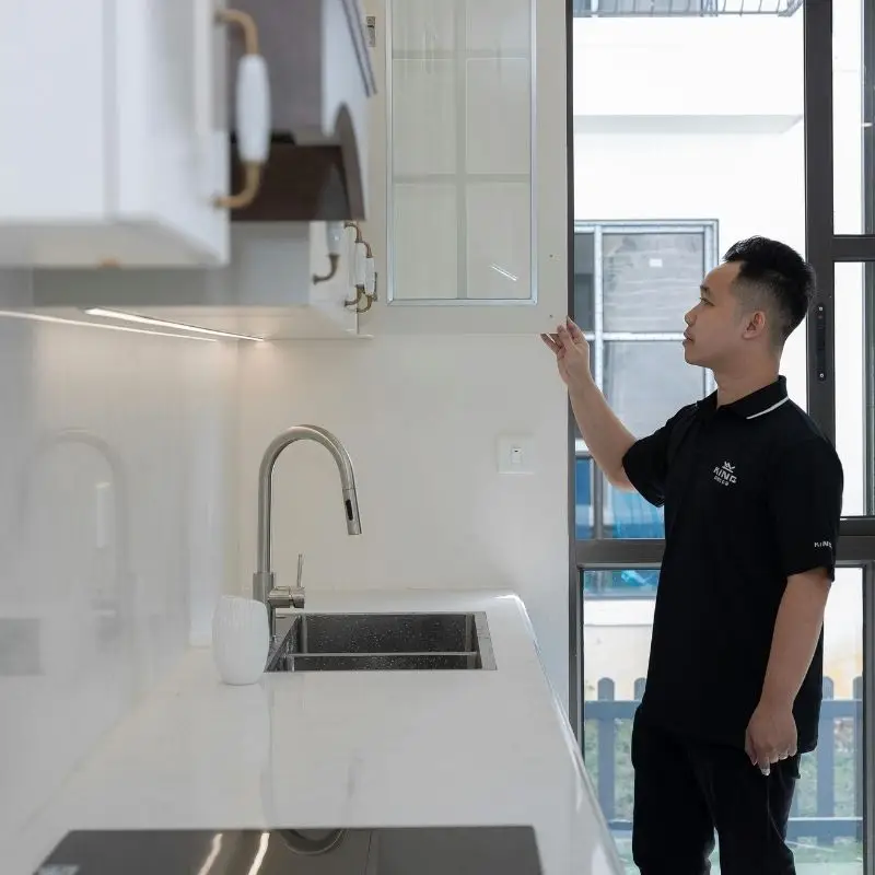 Cleaner checking kitchen hood in apartment